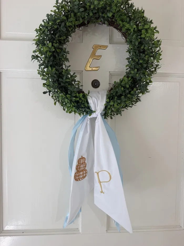 Green wreath with a personalized embroidered white and blue sash